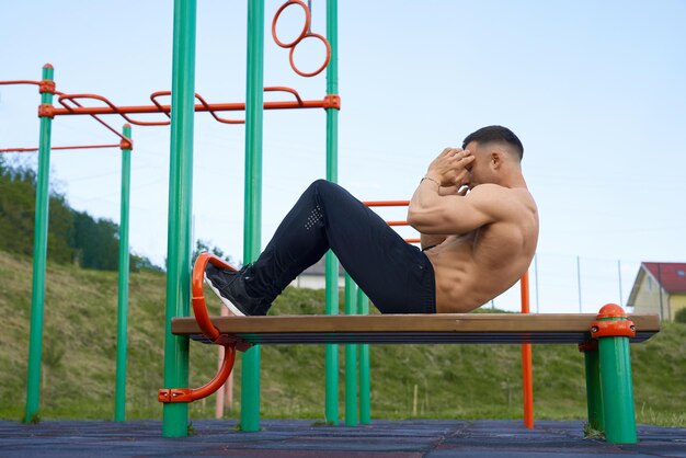 Atleta masculino con torso desnudo haciendo ejercicios abdominales