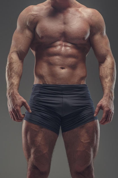 Foto gratuita atleta musculoso sin camisa en bragas negras aisladas sobre fondo gris.