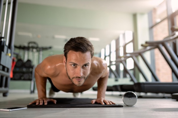 Atleta musculoso ejerciendo pushup en el club de salud