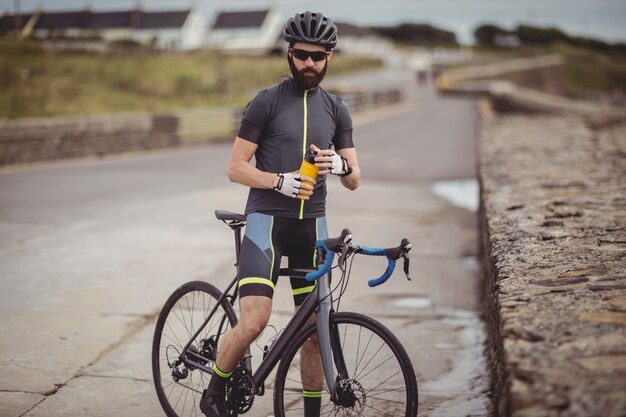 Atleta refrescándose de botella mientras monta en bicicleta