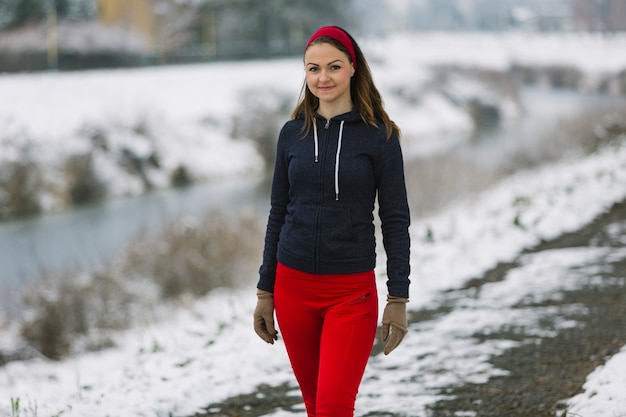 Atleta de sexo femenino joven sonriente que se coloca en invierno