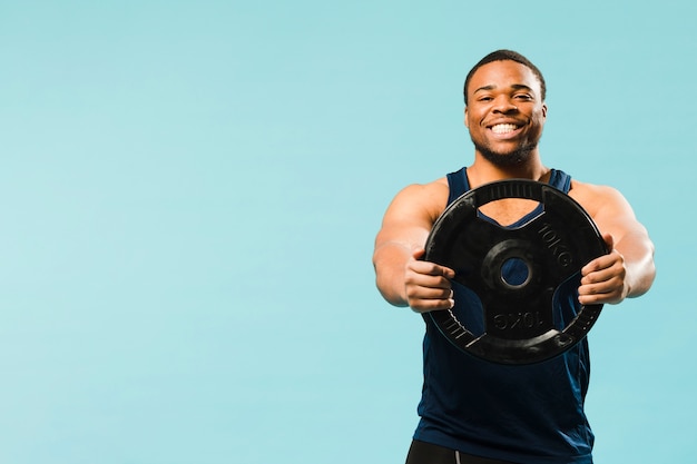 Atleta sonriente sosteniendo pesas con espacio de copia