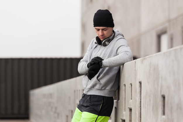 Foto gratuita atleta sujetándose contra un muro mirando el reloj