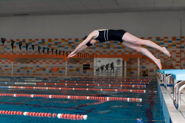 Atleta de tiro completo saltando en la piscina