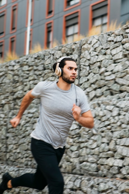 Foto gratuita atleta urbano al lado de muro de piedras