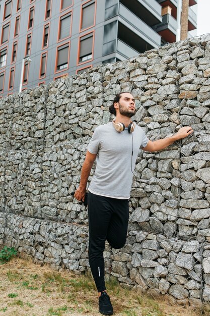 Atleta urbano al lado de muro de piedras