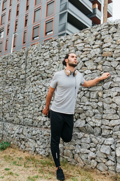 Atleta urbano al lado de muro de piedras