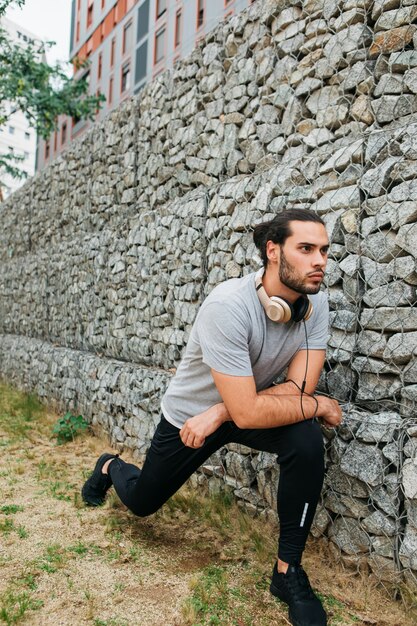 Atleta urbano al lado de muro de piedras