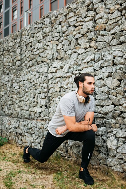 Foto gratuita atleta urbano al lado de muro de piedras