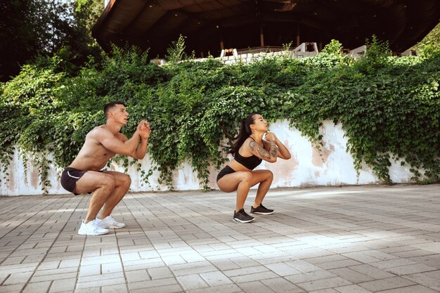 A atletas musculosos haciendo ejercicio en el parque. Gimnasia, entrenamiento, entrenamiento físico, flexibilidad.