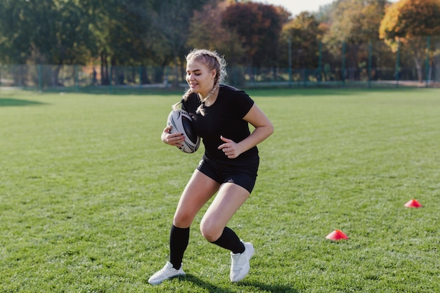 Atlética mujer rubia sosteniendo una pelota de fútbol