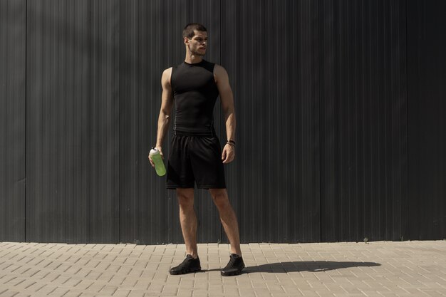 Atlético joven moderno posando en una pared metálica gris