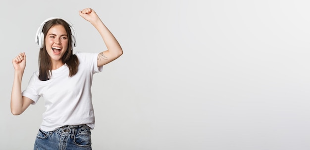 Foto gratuita atractiva chica alegre bailando en auriculares inalámbricos escuchando música