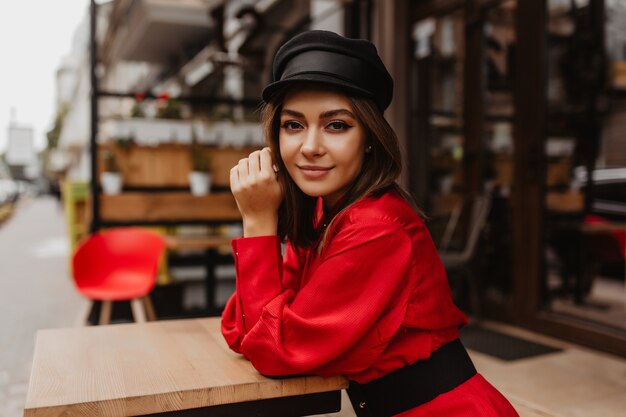 Atractiva chica de cabello oscuro con mirada profunda y hermosas cejas posa para retrato de primer plano contra street cafe