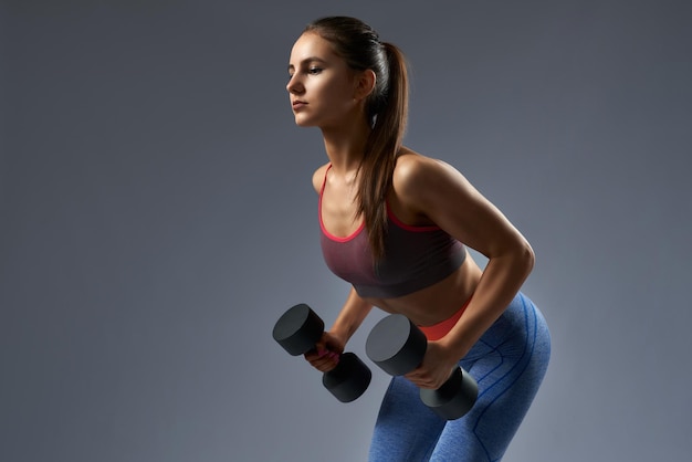 Foto gratuita atractiva chica fitness confiada bombeando músculos bíceps