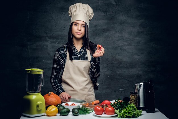 Atractiva cocinera preparando jugo de vegetales en una licuadora.