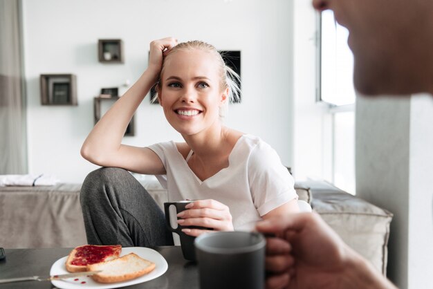 Atractiva dama alegre mirando a su hombre mientras desayunan