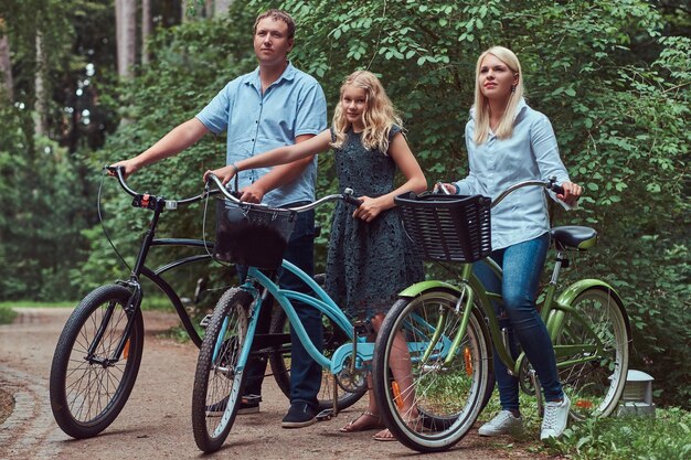 Una atractiva familia vestida con ropa informal en un paseo en bicicleta con su lindo perrito spitz.