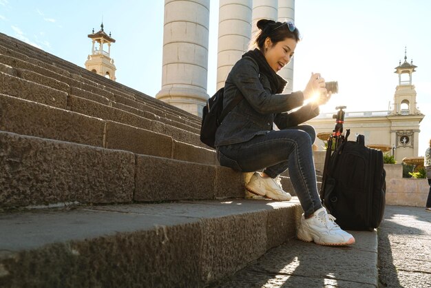 Atractiva y hermosa mochila de viaje de vestimenta casual femenina asiática tomar una foto con una cámara digital con una sonrisa y alegría con el fondo del concepto de viaje de arquitectura de construcción de Europa