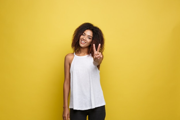 Atractiva hermosa mujer afroamericana posting jugar con su cabello rizado afro. fondo amarillo del estudio. espacio de la copia.