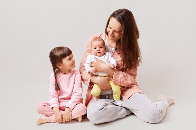 Atractiva joven madre dos hijas sentadas en el suelo