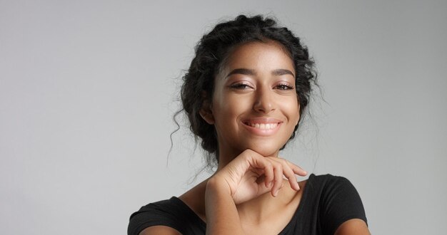 Atractiva joven modelo del Medio Oriente tocando su cara bonita con una piel impecable y sonriendo