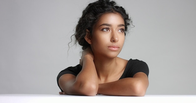 Atractiva joven modelo del Medio Oriente tocando su cara bonita con una piel impecable y sonriendo