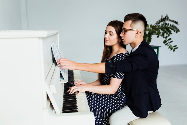 Una atractiva joven pareja tocando juntos el piano.