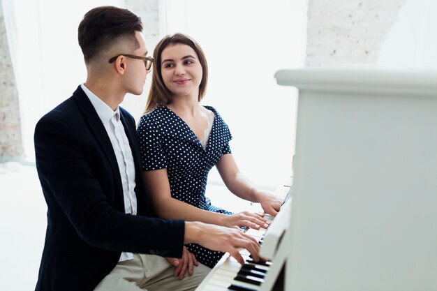 Una atractiva joven pareja tocando el piano mirando el uno al otro