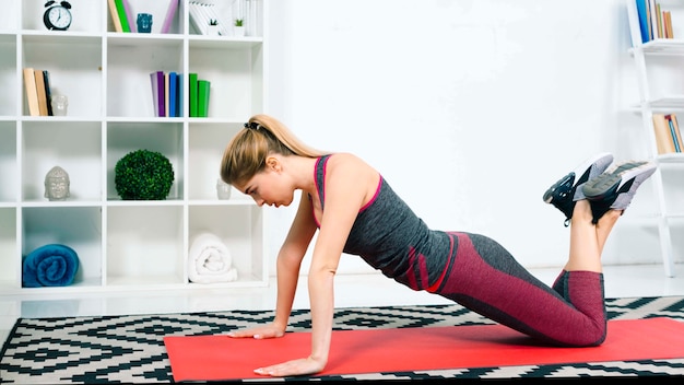 Foto gratuita una atractiva joven practicando yoga en casa