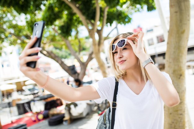 Atractiva joven turista juguetón está haciendo selfie en el teléfono fuera