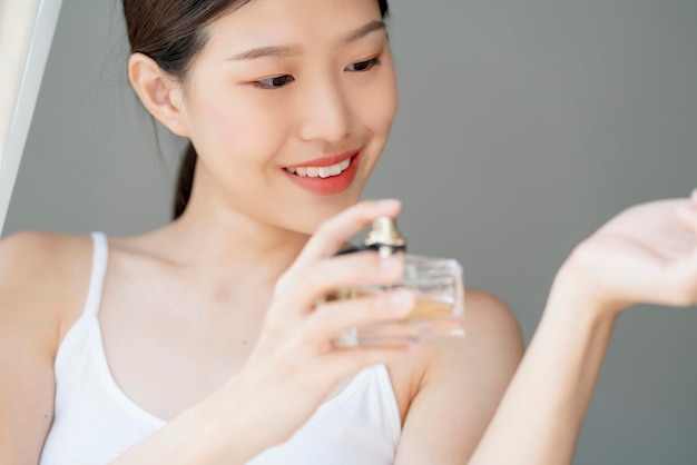 Atractiva mujer adolescente hermosa asiática disfruta de un nuevo perfume en el fondo de su casa de muñeca