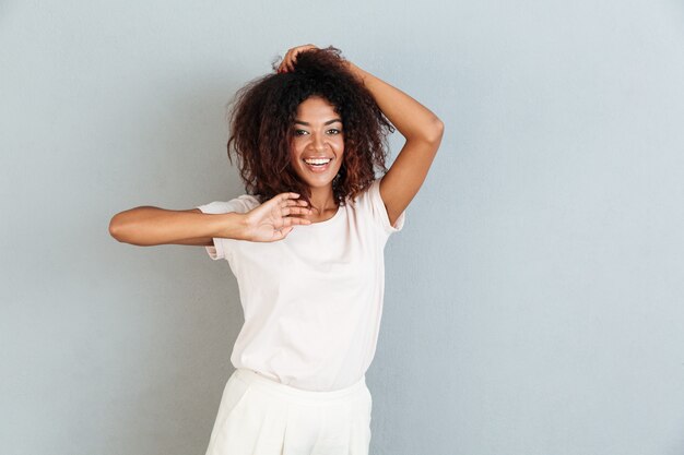 Atractiva mujer africana casual sonriendo y jugando con su cabello