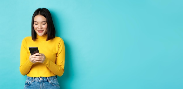 Foto gratuita atractiva mujer asiática leyendo la pantalla del teléfono inteligente y sonriendo redes sociales con personal de telefonía móvil