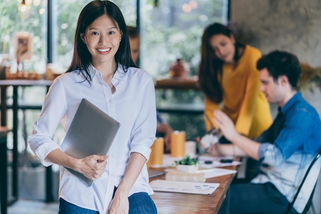 Atractiva mujer asiática sonríe con felicidad y confianza con el trabajo en equipo reuniéndose con el concepto de ideas de inicio de fondo