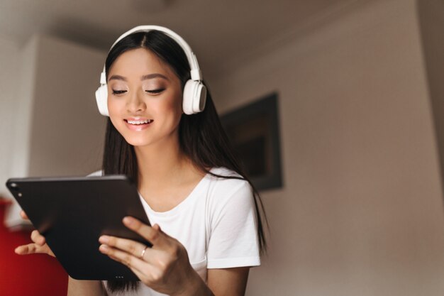 Atractiva mujer asiática con sonrisa se ve en tableta