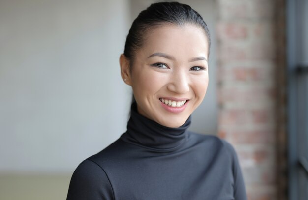Atractiva mujer asiática con un traje negro sonriendo suavemente