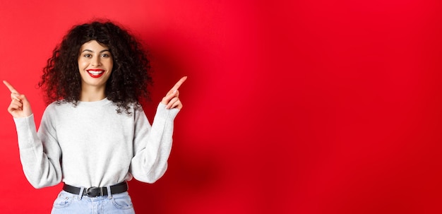 Foto gratuita atractiva mujer caucásica que muestra el camino señalando con el dedo de lado a dos promociones que demuestran la variante