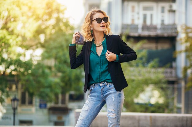 Foto gratuita atractiva mujer elegante caminando en la calle de la ciudad con bolso, vestida con chaqueta negra, segura y sexy,