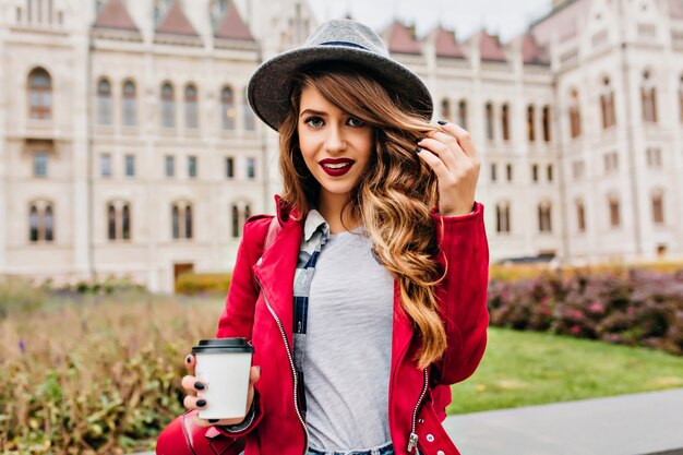 Atractiva mujer elegante posando con una sonrisa suave y sosteniendo una taza de café en la mañana