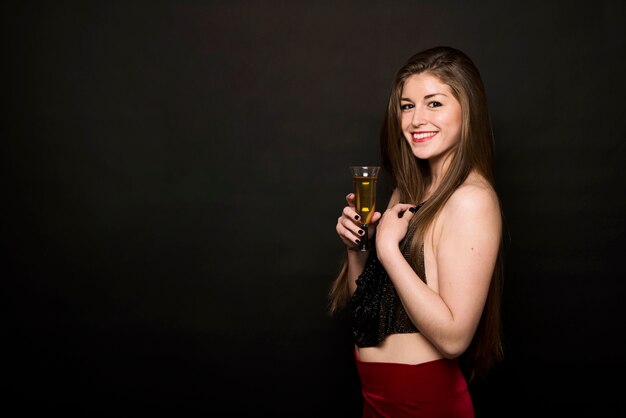 Atractiva mujer feliz en paño de noche con vaso de bebida