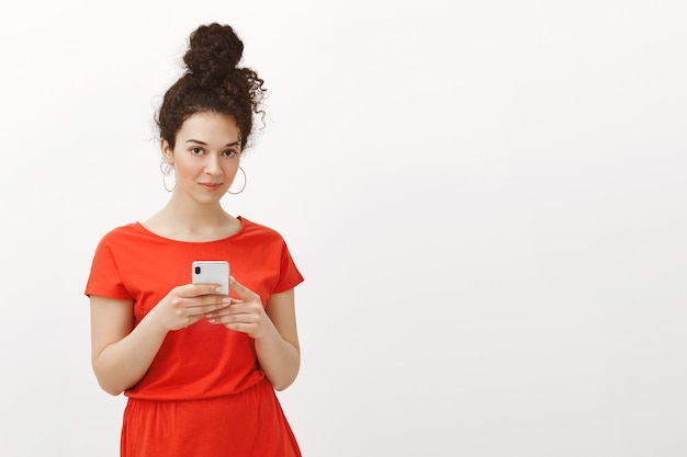 Foto gratuita atractiva mujer femenina con estilo con el pelo rizado peinado en moño en vestido rojo