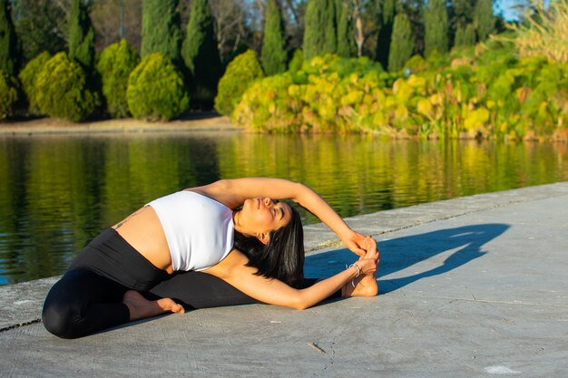 Atractiva mujer haciendo ejercicio cerca del lago con hermosa ropa deportiva