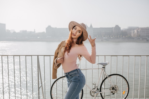 Atractiva mujer jengibre viste camisa rosa disfrutando de un día soleado cerca del mar