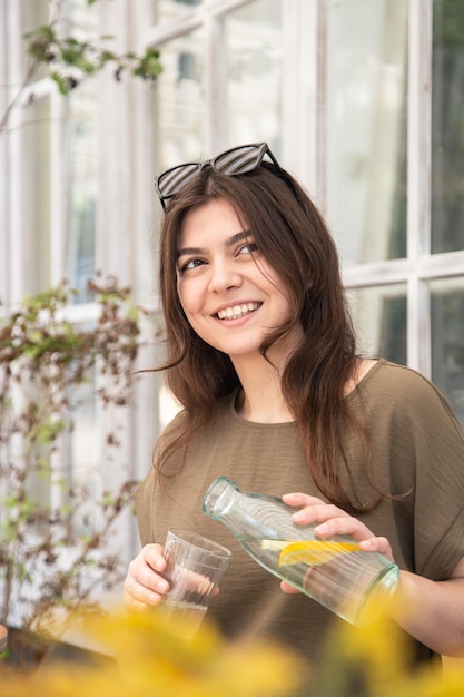 Atractiva mujer joven bebe agua con limón