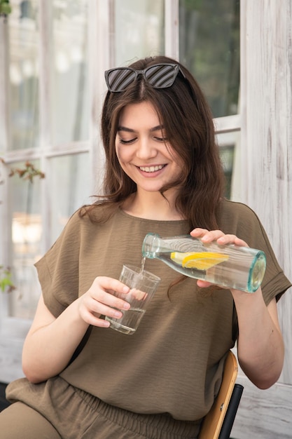 Atractiva mujer joven bebe agua con limón