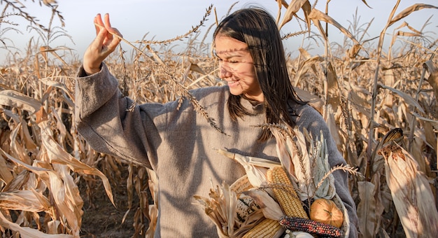 Atractiva mujer joven en un campo de maíz con una cosecha de otoño