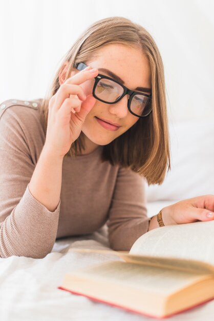 Una atractiva mujer joven con gafas leyendo libro