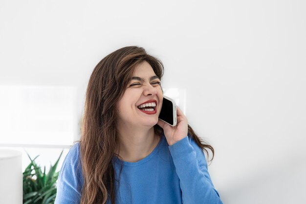 Atractiva mujer joven hablando por teléfono en un espacio de copia interior blanco