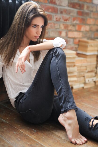 Atractiva mujer joven posando con una camisa blanca y jeans